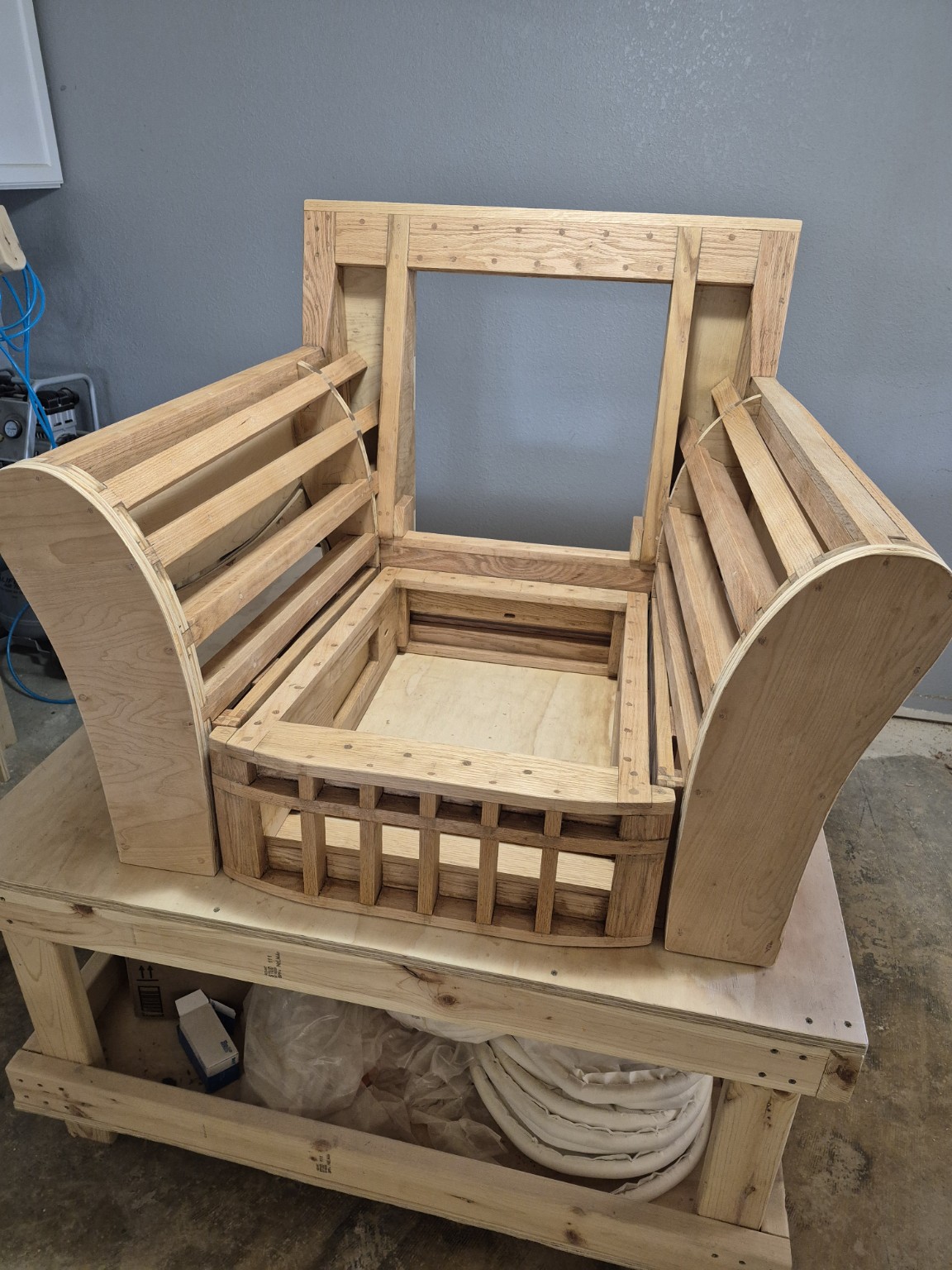 Exposed wooden armchair frame showing the rails, braces, and shaped arm structure beneath the upholstery