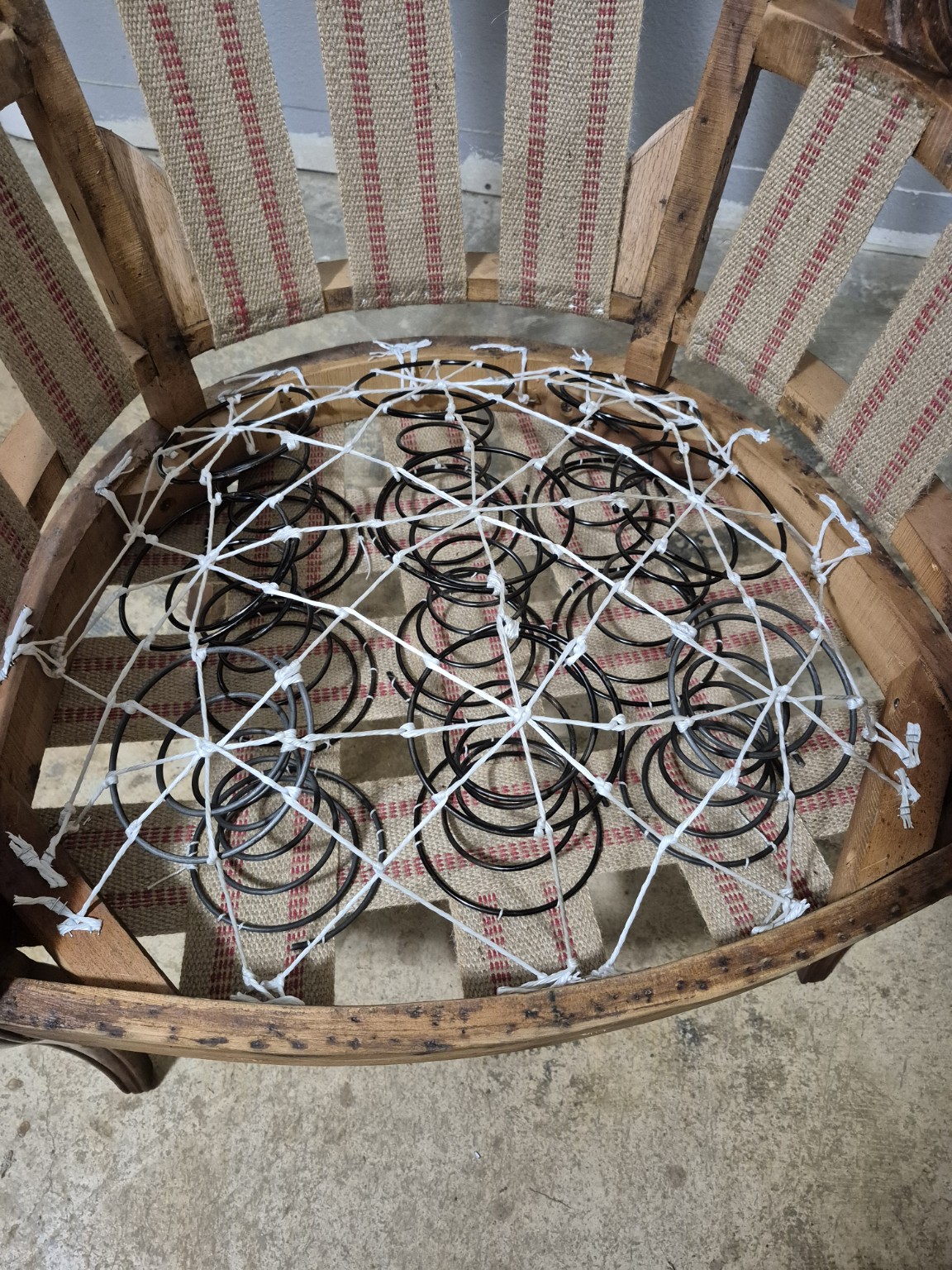 Chair seat under construction, with coil springs tied together over woven webbing